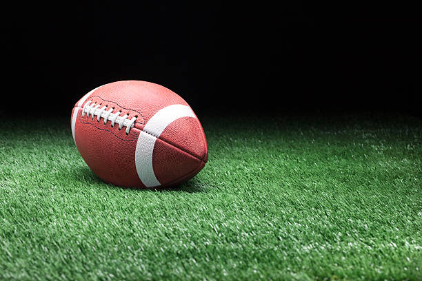 istock Football on grass against dark background 477431413