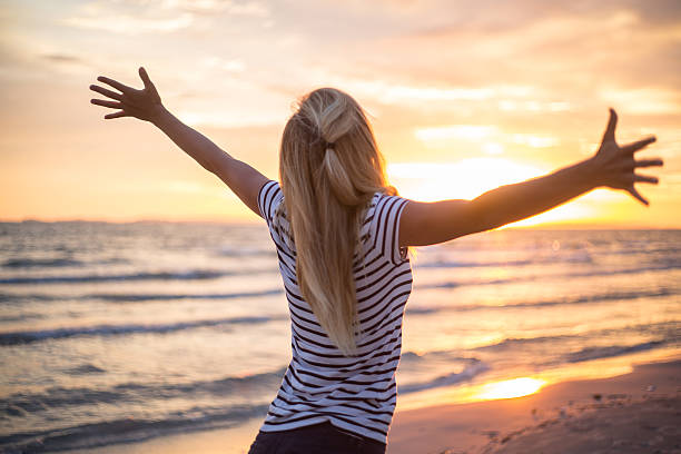 istock Cheering woman open arms to sunset at seaside 477433790