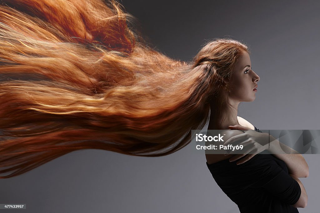 Beautiful woman with red hair Beautiful red headed woman with long hair flying against gray background, side view Side View Stock Photo