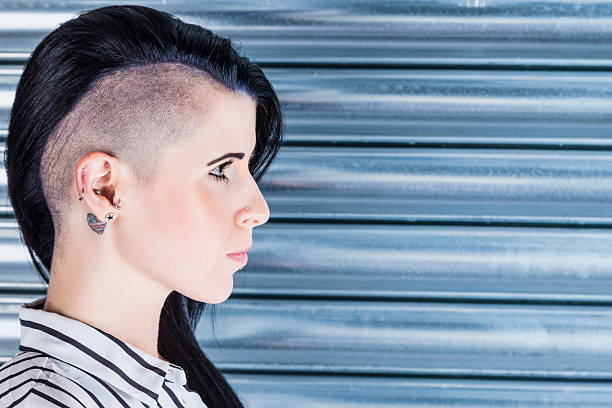 Woman With A Part-shaved Head And Tattoos Profile portrait of a pretty 'alternative' Caucasian woman with a part-shaved head and tattoo. half shaved hairstyle stock pictures, royalty-free photos & images