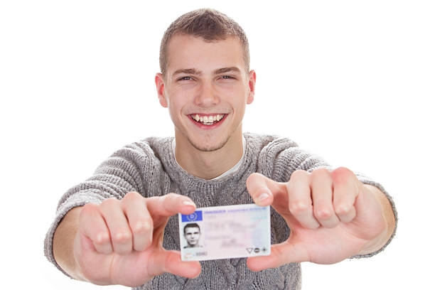 молодой человек, показывая его водитель лицензия - secret identity фотографии стоковые фото и изображения