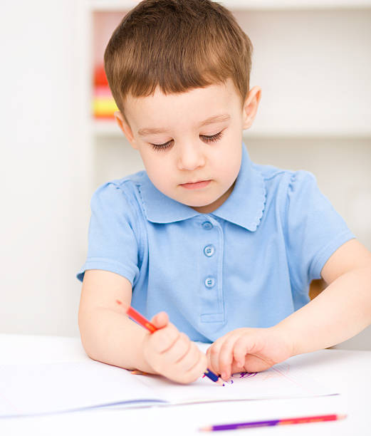 istock Little boy is drawing on white paper 477437997