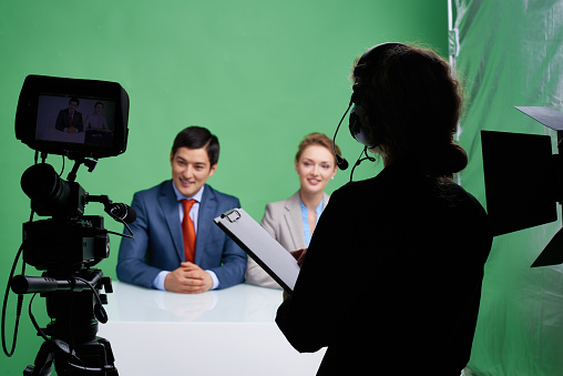 Charismatic tv reporters hosting tv program, while camera operator looking at them