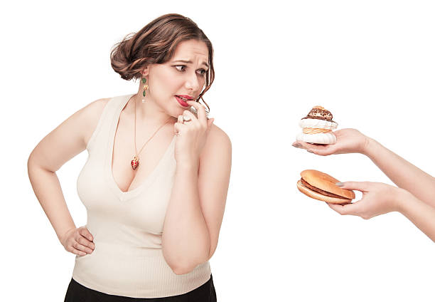istock Plus size woman seduced with hamburger and pastry 477441287
