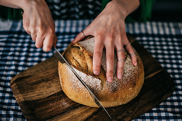 istock Young woman cutting freshly made bread 477445770