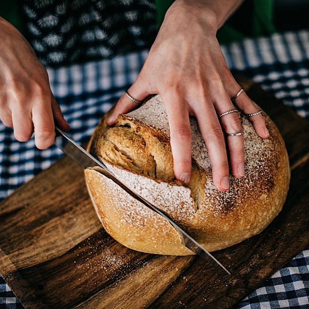 istock Young woman cutting freshly made bread 477445778