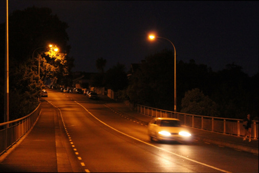 Moody shot of a lone car on the road at night.