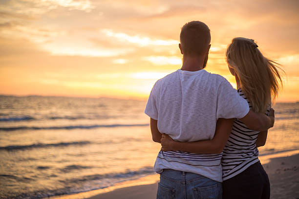istock Cheerful couple on beach watching sunset 477447086