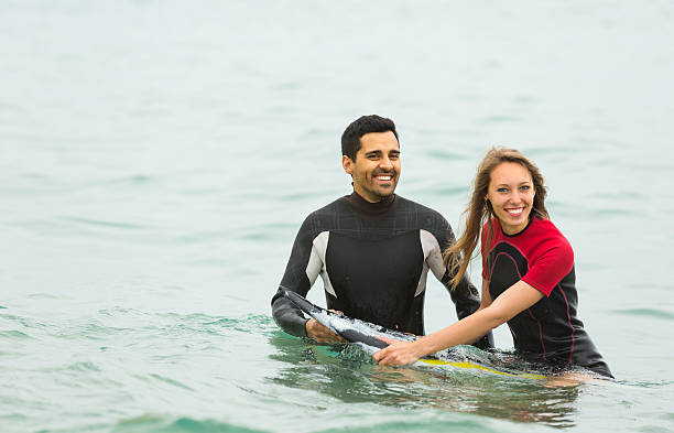 istock Couple in wetsuits with surf boards 477449852