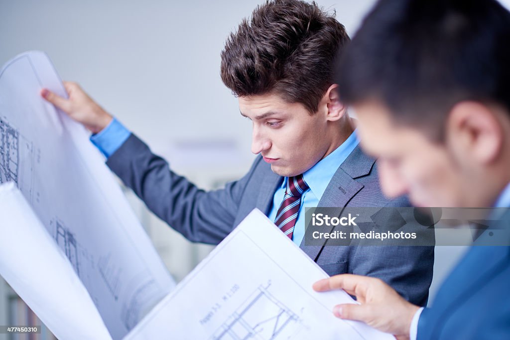 Examining a plan Two engineers examining construction plan 2015 Stock Photo