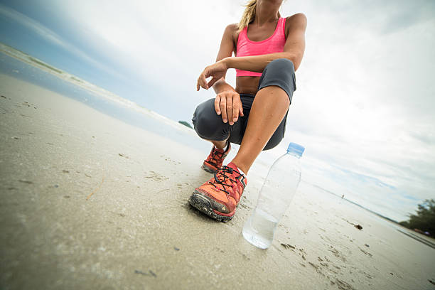 Young woman on the beach on a cloudy day having a break from her morning jogging.