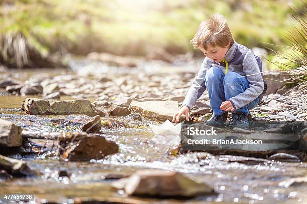 Boy Sailing A Paper Boat Stock Photo - Download Image Now - Child, Stream - Body of Water, Playing