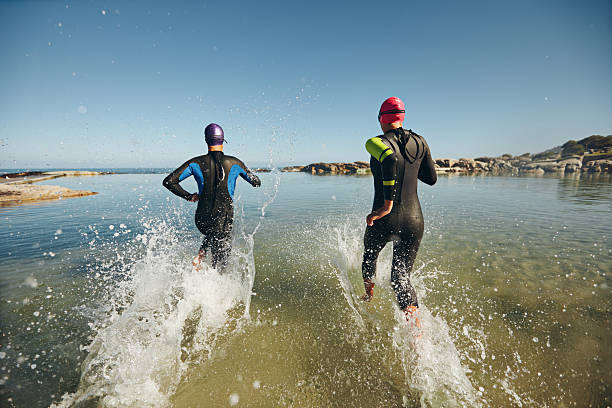 dos atletas que compiten en un triatlón - swimming exercising women back fotografías e imágenes de stock