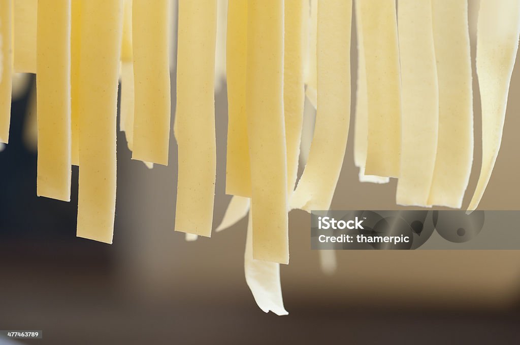 Fresh homemade Italian Tagliatelle Pasta hung up for drying Fresh handmade Italian pasta hanging off a rack before cooking Cooking Stock Photo