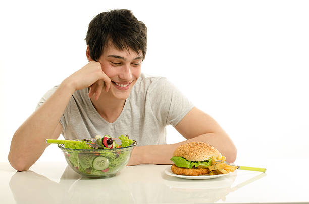 istock Man choosing between a bowl of salad and big hamburger. 477464318