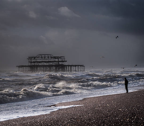 istock Man standing on the shoreline by stormy sea, Brighton, UK 477470139