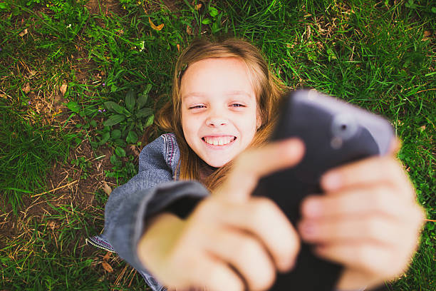 istock Girl laying on grass with mobile phone 477470460