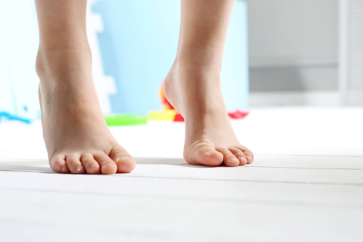 Child's bare feet on the wooden floor 