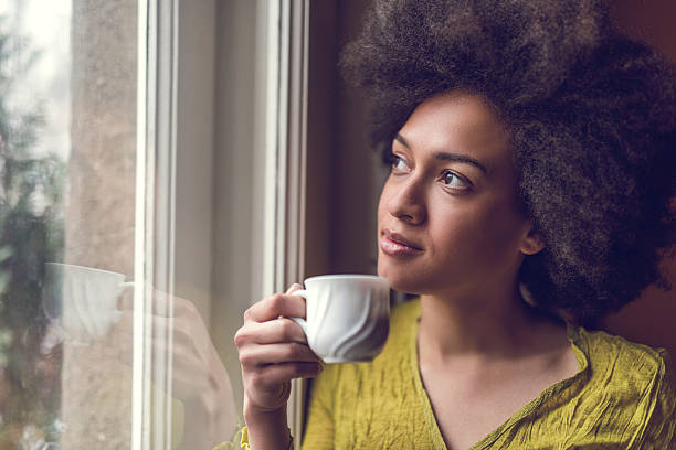 istock Young pensive African American woman looking through window. 477474608