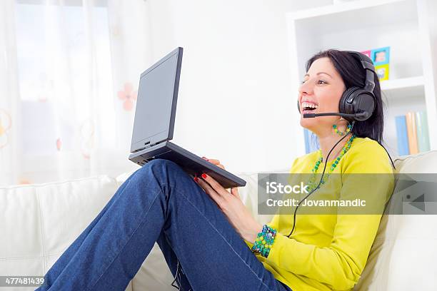 Woman On Sofa Using Laptop And Headset At Home Stock Photo - Download Image Now - 30-39 Years, Adult, Adults Only