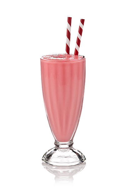 Classic glass of strawberry milkshake on white backdrop.