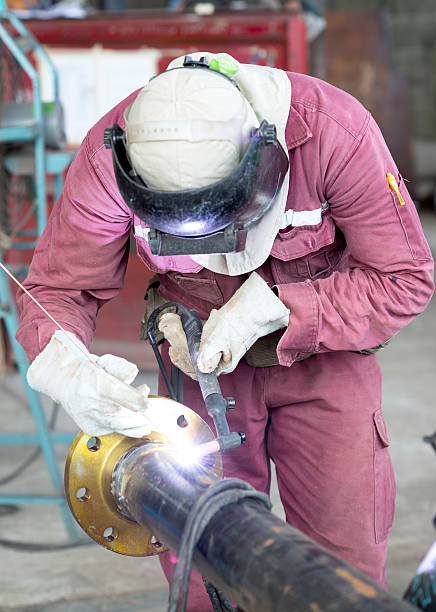istock Craftsman in a safety suit is welding a metal pipe 477483711