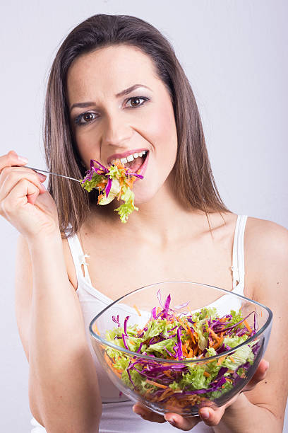 istock Young woman eating healthy salad 477487401