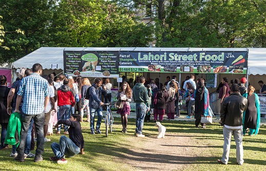 Glasgow, Scotland, UK - 15th June 2015: A queue of people attending Glasgow Mela, waiting to be served at the Lahori Street Food and Just Vegetarian stalls both owned by Shangreela Caterers, a supplier of Indian Subcontinent food based in Huddersfield. Glasgow Mela is a free-entry multicultural festival held in Kelvingrove Park. 2015 marked its 25th anniversary.