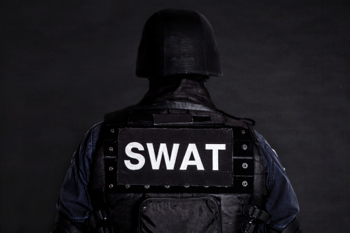 Special weapons and tactics (SWAT) team officer on black background shot from behind