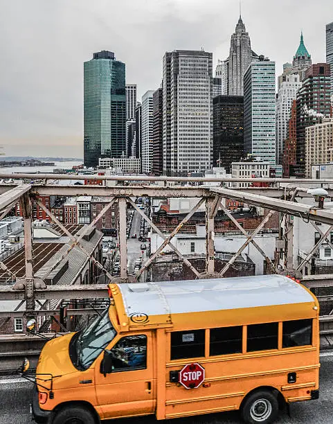 Yellow schoolbus driving on the Brooklyn Bridge.