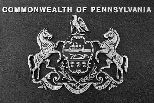 Photo of a bas-relief, silver on black, of the coat of arms of the Commonwealth of Pennsylvania with the state motto \