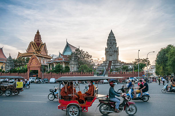 verkehr außerhalb wat ounalom bei sonnenuntergang in phnom penh, kambodscha - national landmark editorial color image horizontal stock-fotos und bilder