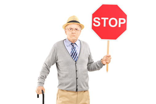 Angry mature gentleman holding a stop sign isolated on white background