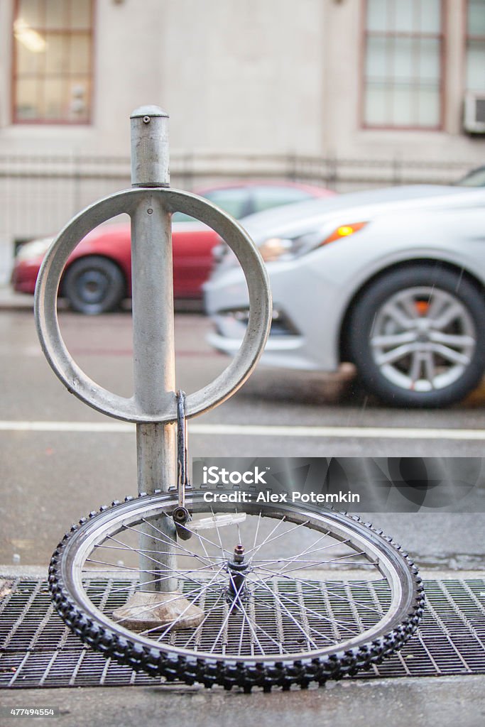 Bicycle wheel binded to a parking pillar A bicycle wheel binded to a parking pillar at the street in Manhattan 2015 Stock Photo