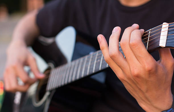 istock young man playing an acoustic guitar on the beach 477504100