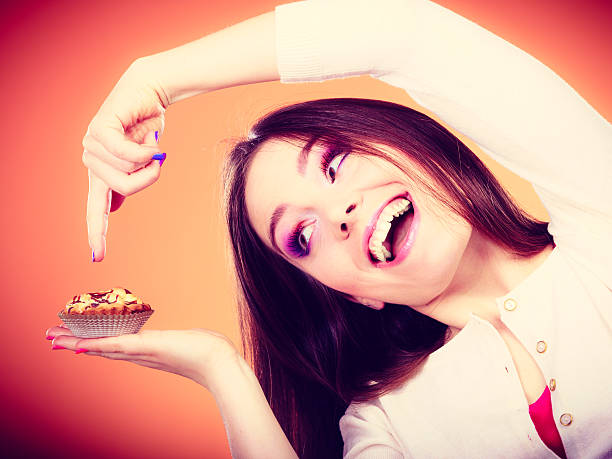 istock Smiling woman holds cake in hand pointing with finger 477511736