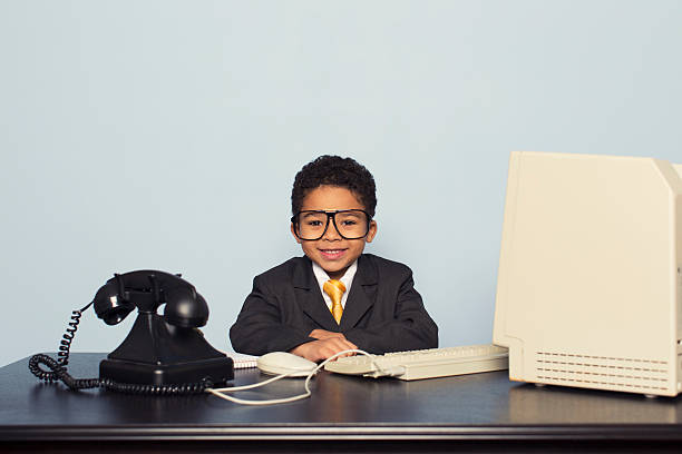 istock Young Boy Sits at Retro Computer in Business Office 477513417