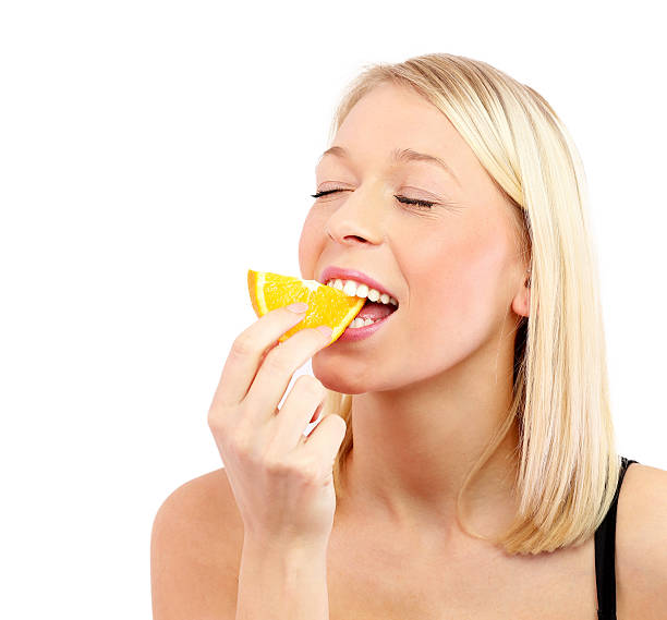 istock Pretty blonde eating Orange fruit -isolated headshot 477514129