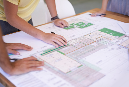 Shot of a group of architects reviewing blueprints spread out on a table