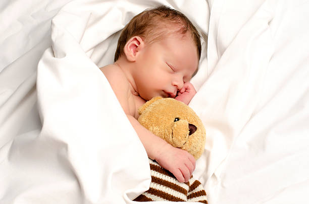 istock Beautiful innocent newborn sleeping with teddybear. 477517340