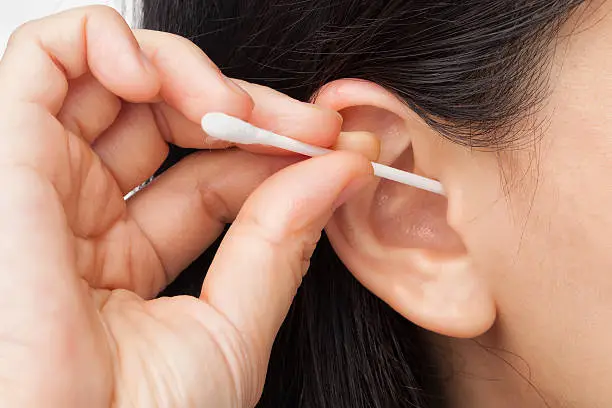 Woman cleaning ear using cotton stick