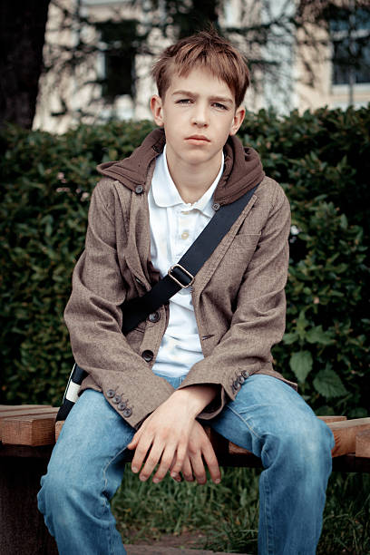 istock Sad teenager sitting on bench in park 477518975
