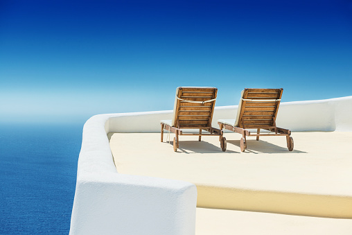 Empty Sun Lounge Chair on balcony by the sea In Santorini at Sunrise.