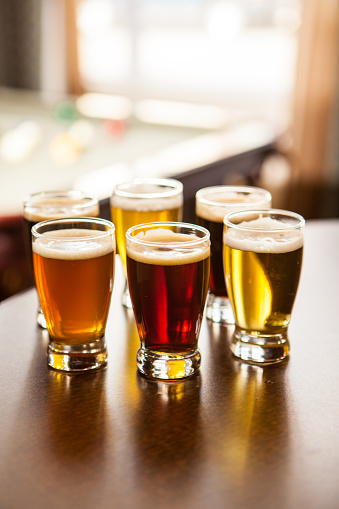 Six glasses of various types of beer on a bar.