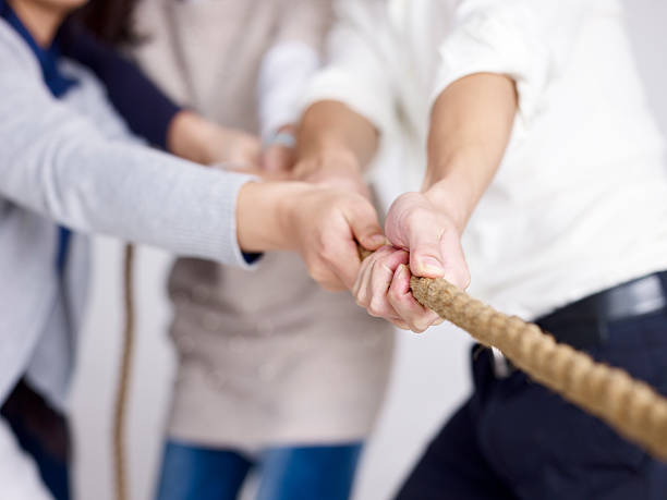 group of business people playing tug-of-war stock photo