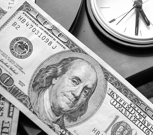 Stack of one hundred dollar bills  with clock stock photo