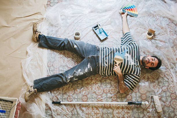 Exhausted man resting after hard painting work One young man is lying down on the floor after a hard days work painting his new apartment. painter tired stock pictures, royalty-free photos & images
