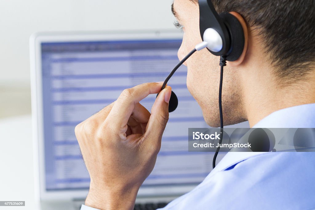 man wearing headset looking at monitor man wearing headset looking at computer monitor Call Center Stock Photo