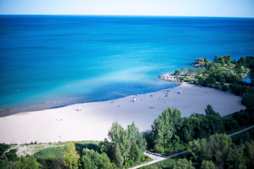 Looking down from atop a cliff to the sandy beach below at the crystal blue waters edge