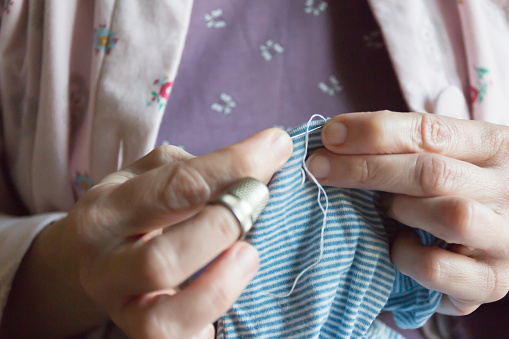 hemming a dress, woman hands needlework, detail of sewing hand